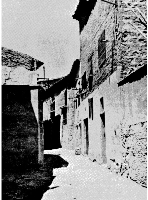 Photographie en noir et blanc d'une ruelle pavée dans l'ancien quartier juif de Tudèle, en Espagne — façades de pierre et puits central.