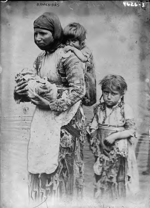 Photographie ancienne sépia montrant une mère et un enfant arméniens en haillons, debout, le regard hagard.