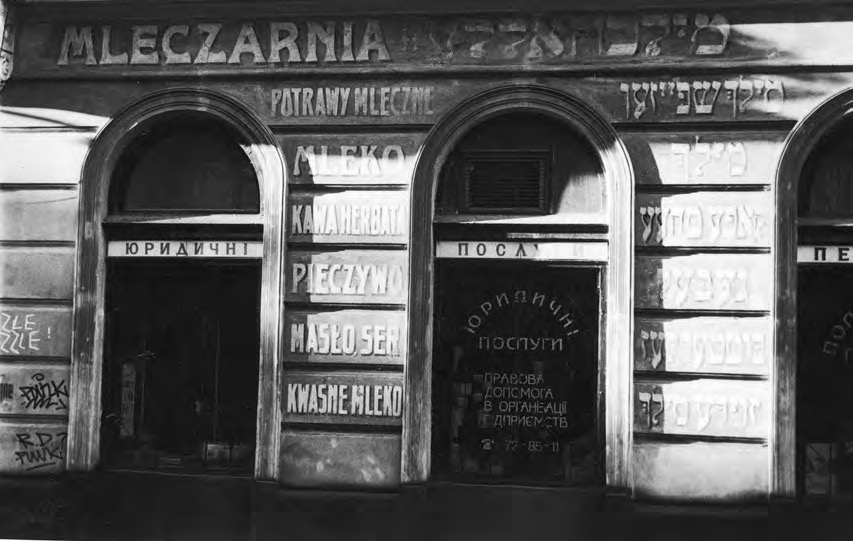 Façade d'une laiterie ukrainienne ancienne, devanture aux arcades et lettrage cyrillique sur fond gris.