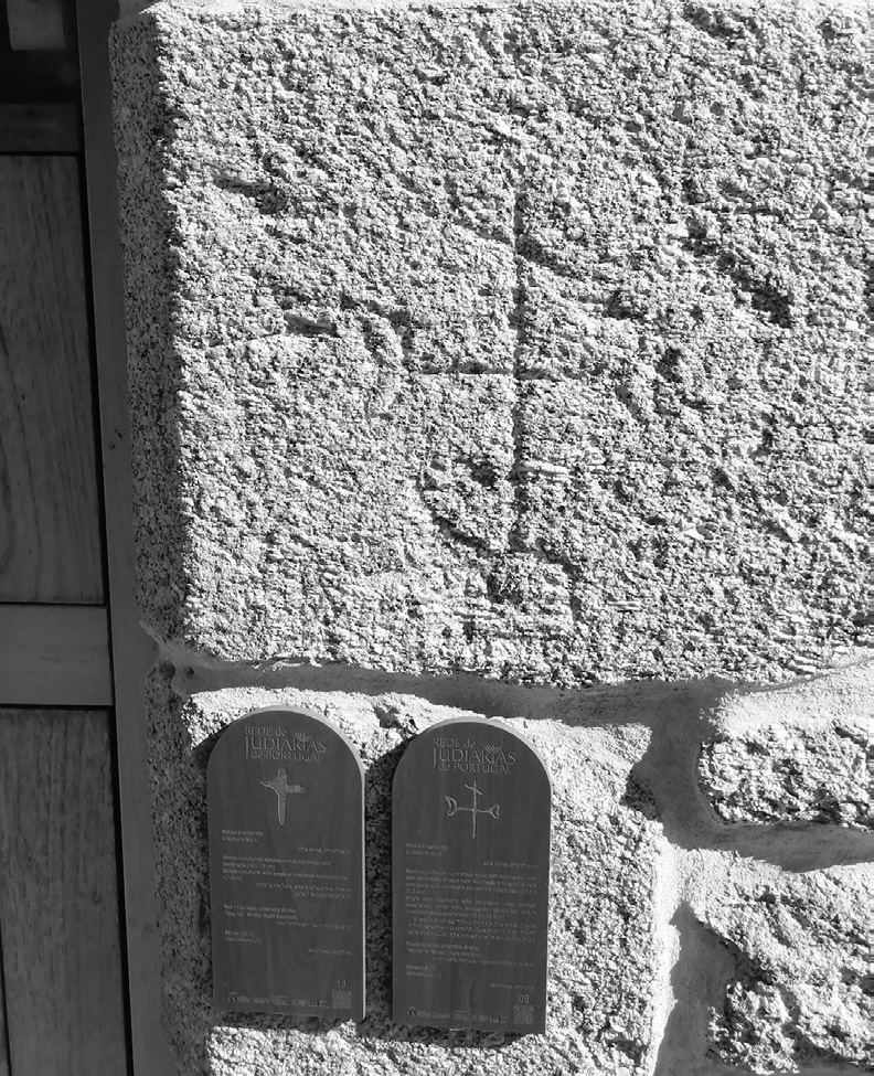 Photographie d'un mur de pierre brute de Belmonte où sont sculptés une croix et, en-dessous, deux petits blocs évoquant les Tables de la Loi.